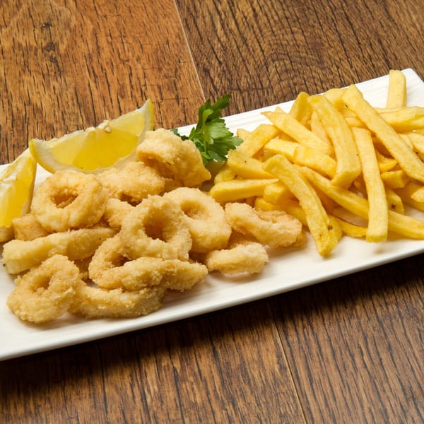 Crispy fried calamari rings and golden french fries with lemon wedges and parsley on a white plate.