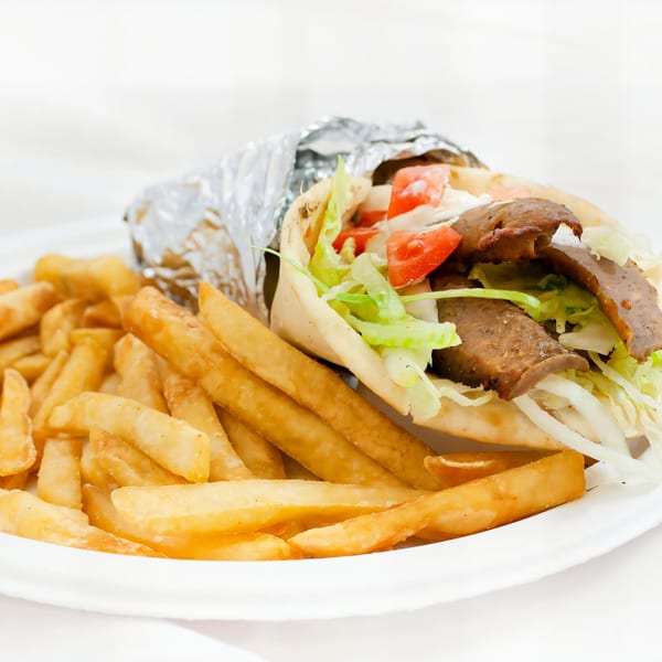 A gyro wrapped in foil with fries on a white plate from AJ's Pizza, Subs, and Wings.
